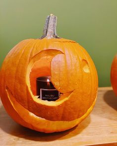 a carved pumpkin sitting on top of a wooden table with a candle in the center