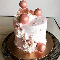 a white cake with pink and gold decorations on it's side sitting on a wooden platter