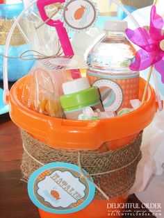 an orange bucket filled with baby items on top of a table