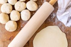 doughnuts and rolling pin on a wooden cutting board with flour next to it