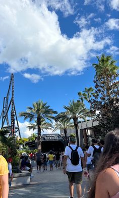 people are walking around in front of the roller coaster