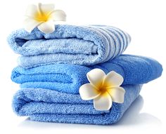 towels stacked on top of each other with two white and one blue flowers in the middle