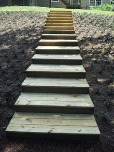 a set of wooden steps leading up to a house in the background with grass and trees