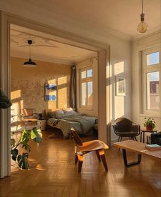 a bedroom with wooden floors and lots of light coming in from the windows on the wall