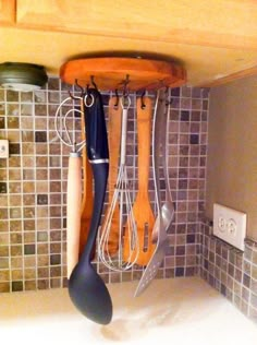 kitchen utensils hanging from the ceiling in a kitchen with tiled backsplash