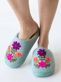 a woman's feet wearing slippers with flowers on them