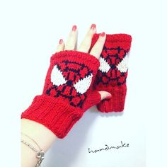 a woman's hand wearing red knitted mitts with white hearts on them