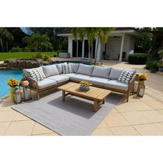 a couch and coffee table in front of a swimming pool with flowers on the side