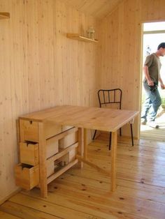 a man walking into a room with wooden floors and walls, while another person walks in the background