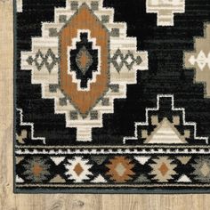 a black and brown rug with an orange design on the bottom, sitting on a wooden floor