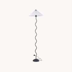 a floor lamp with a white shade on it's side and a black base