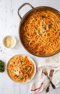 a pan filled with pasta and sauce next to a bowl of parmesan cheese