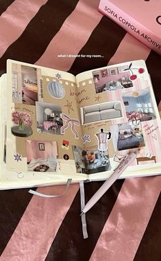 an open book sitting on top of a bed next to a pink and black striped blanket