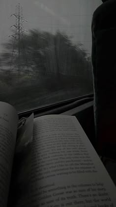 an open book sitting in front of a window on top of a train car next to a power line