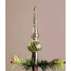 a tall metal pole with a christmas tree decoration on it's top and two red balls hanging from the poles