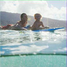 a man and child are in the water on surfboards