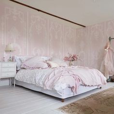 a bedroom with pink wallpaper and white furniture