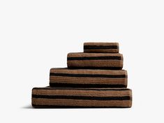 three towels stacked on top of each other in front of a white wall with black and brown stripes