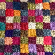 a multicolored knitted blanket that is very colorful and has squares on it