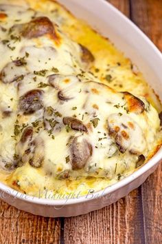 a casserole dish with cheese and mushrooms in it on a wooden table top