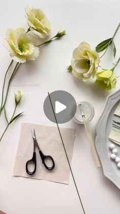 flowers and scissors on a table with paper, beads, and other things to make it look like they are making something