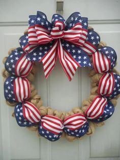 a patriotic wreath with red, white and blue bows on the front door for memorial day