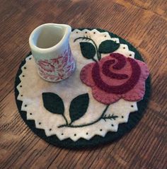 a coffee cup sitting on top of a wooden table next to a flower pot holder