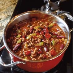 a red pot filled with chili and meat on top of a stove