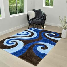 a blue and brown area rug in a living room with two chairs, one black chair and the other white