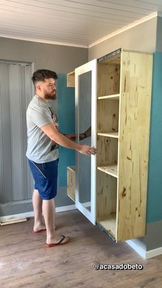 a man standing in front of a cabinet with drawers on the bottom and one drawer open