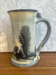 a ceramic mug sitting on top of a wooden table next to a wallpapered background