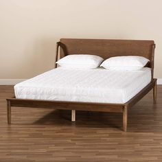 a bed sitting on top of a hard wood floor next to a white wall and wooden floors