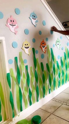 a kid is painting a wall with fish and seaweed on the bottom half of it