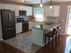 a kitchen with white cabinets and stainless steel appliances is pictured in this image, there are four stools around the island