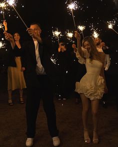 a man and woman holding sparklers in their hands