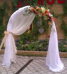 an outdoor wedding arch decorated with flowers and ribbons