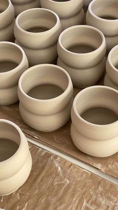 there are many white vases sitting on the table and ready to be made into something