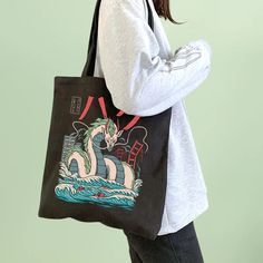 This amazing Spirited Away tote bag features Haku in his dragon shape. The illustration is in a comic style and it pops over the black background. Use to carry books, journals, art materials, or groceries. It has one main compartment that opens easily and fits various-sized items such as an umbrella. Size: 34 cm x 38 cm Material: cotton Anime Tote Bag, Canvas Bag Design, Women Cartoon, Cartoon Dragon, Teacher Bags, Painted Tote, Beg Tangan, Vintage Shoulder Bag, Dragon Pattern