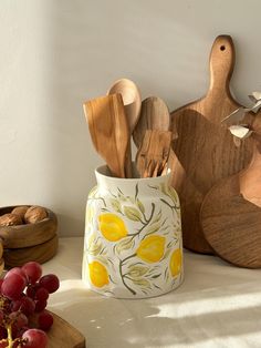 wooden utensils and cutting boards sit on a counter next to grapes, nuts and other kitchen items