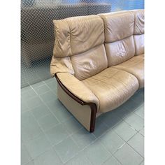 a beige leather couch sitting on top of a tiled floor