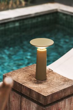 an outdoor table with a candle on it next to a pool