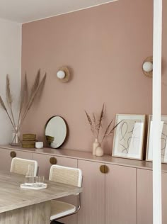 a dining room with pink walls and white chairs