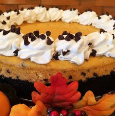 a cake with white frosting and chocolate chips on top, surrounded by autumn leaves