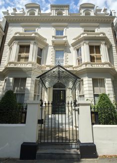 a large white building with an iron gate and entry way leading to the front door