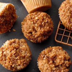 several muffins are on a cooling rack next to some cupcake liners