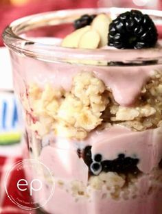 a close up of a dessert in a glass on a table with berries and other toppings