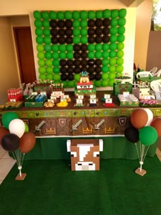 a table topped with balloons and cake next to a giant balloon wall in the shape of a cow