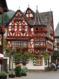 an old building with red and white paint on it's side in the middle of town