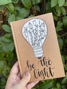 a hand holding up a book with an image of a light bulb on it