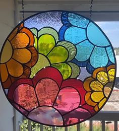 a circular stained glass window with flowers on it's side hanging from a chain